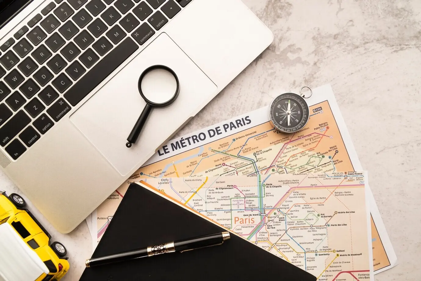 На мраморном фоне — ноутбук и карты.